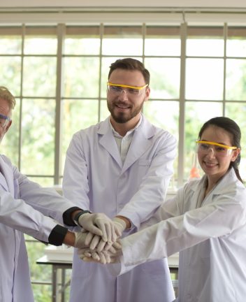 scientists-stacking-hands-laboratory-scaled-1.jpg